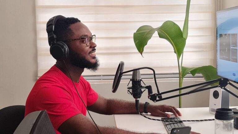Microfon de podcast și căști așezate pe un birou de acasă, lângă un laptop pregătit pentru interviu